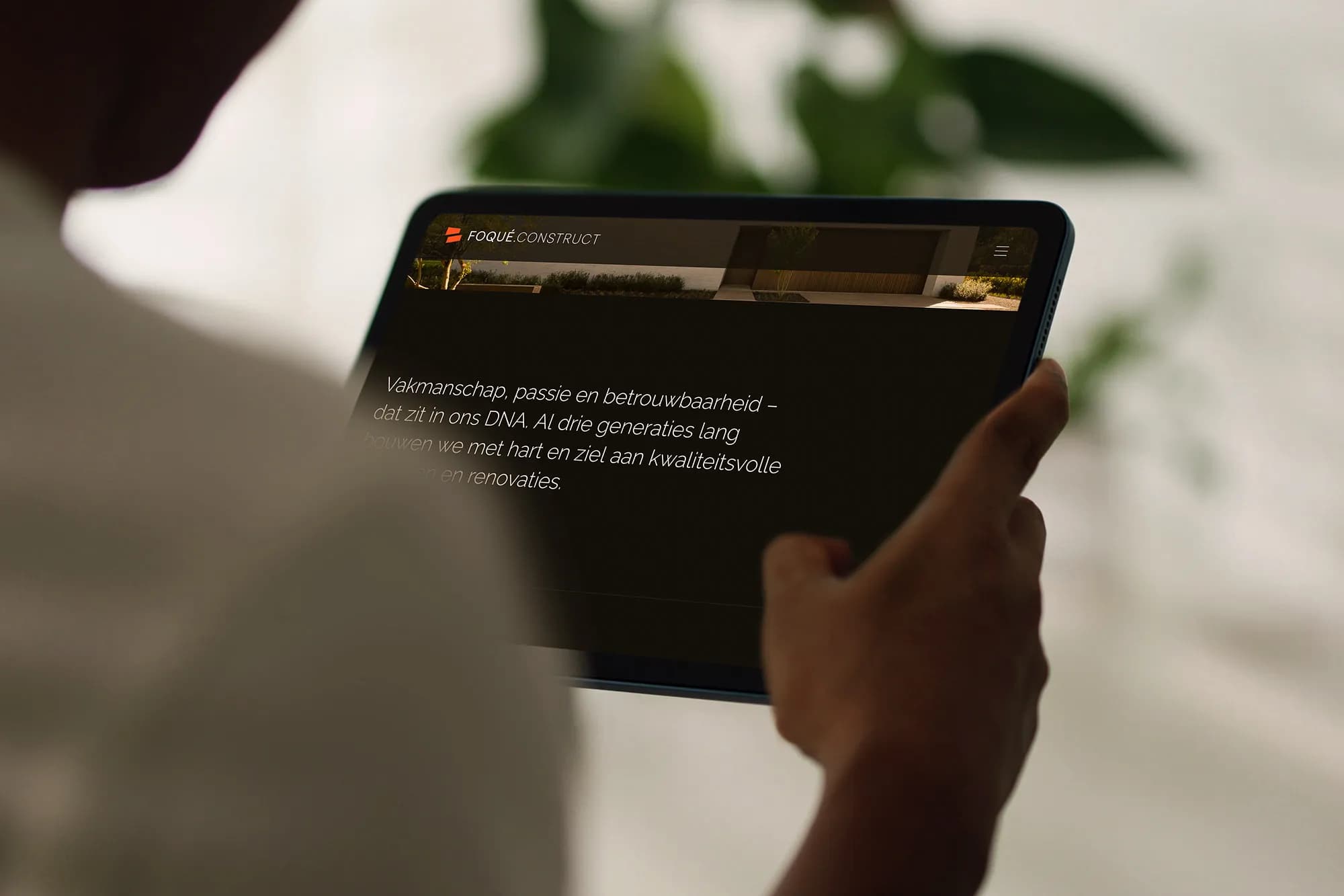 Man houdt een ipad vast waarop de website van Foqué Construct te zien is